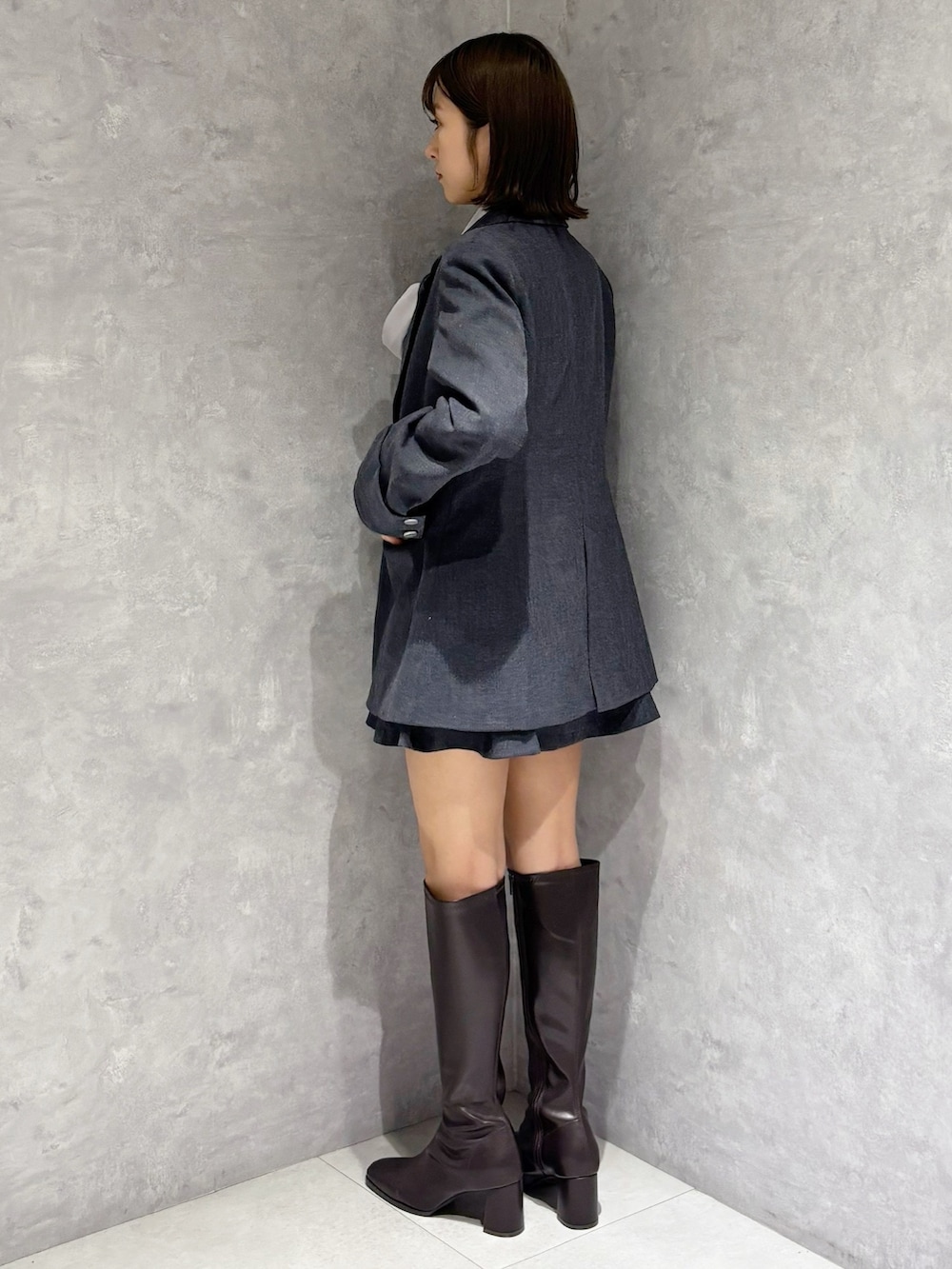 グレー系のスカート、グレー系のテーラードジャケット、ブラウン系のブーツを着用したレディースの冬コーディネートの3枚目の写真