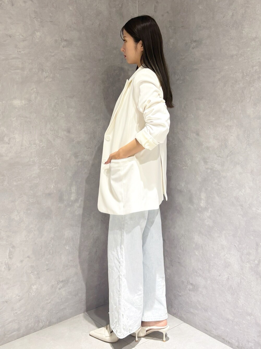 ブルー系のデニムパンツ、ホワイト系のパンプス、ホワイト系のハンドバッグを着用したレディースの冬コーディネートの3枚目の写真