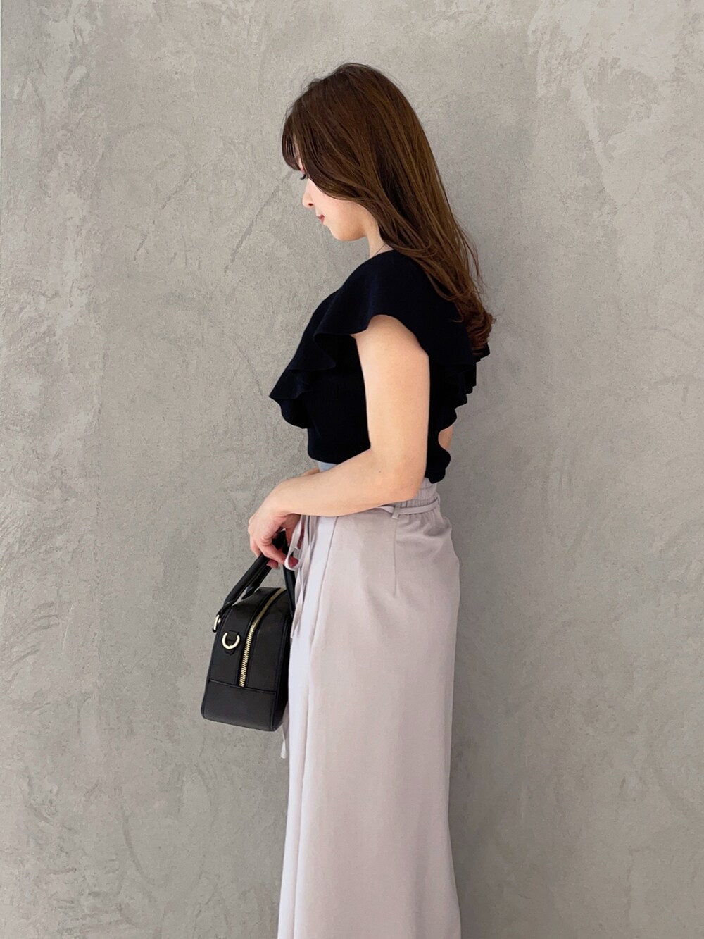 ブラック系のボストンバッグ、ブラック系のニット/セーター、ブラック系のサンダルを着用したレディースの春コーディネートの5枚目の写真