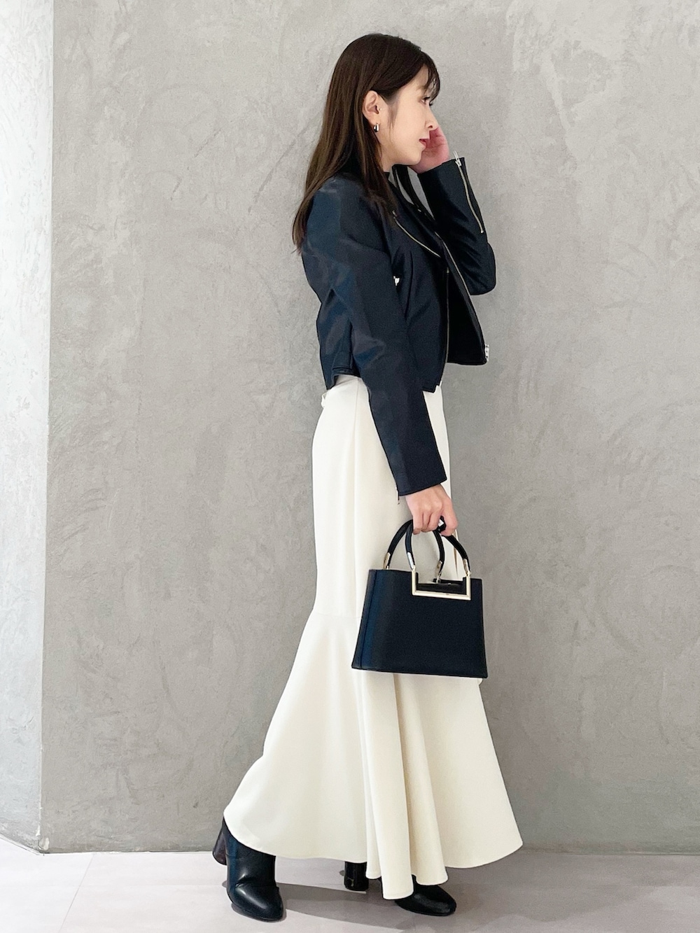 ブラック系のハンドバッグ、ブラック系のブーツ、ブラック系のライダースジャケットを着用したレディースの冬コーディネートの3枚目の写真