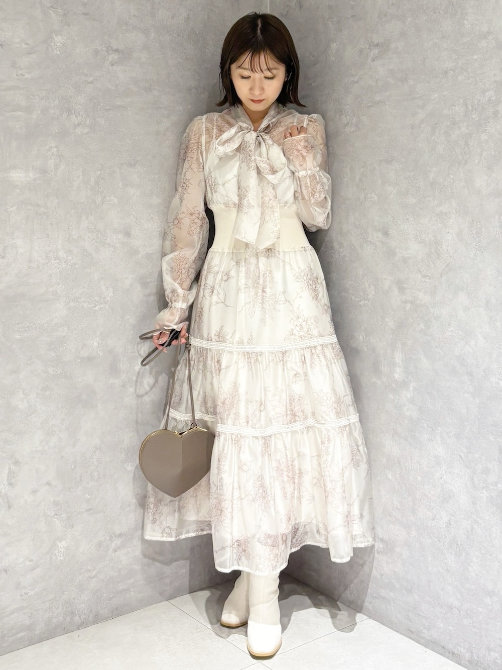 ベージュ系のショルダーバッグ、ホワイト系のブーツ、ベージュ系のワンピースを着用したレディースの冬コーディネートの5枚目の写真