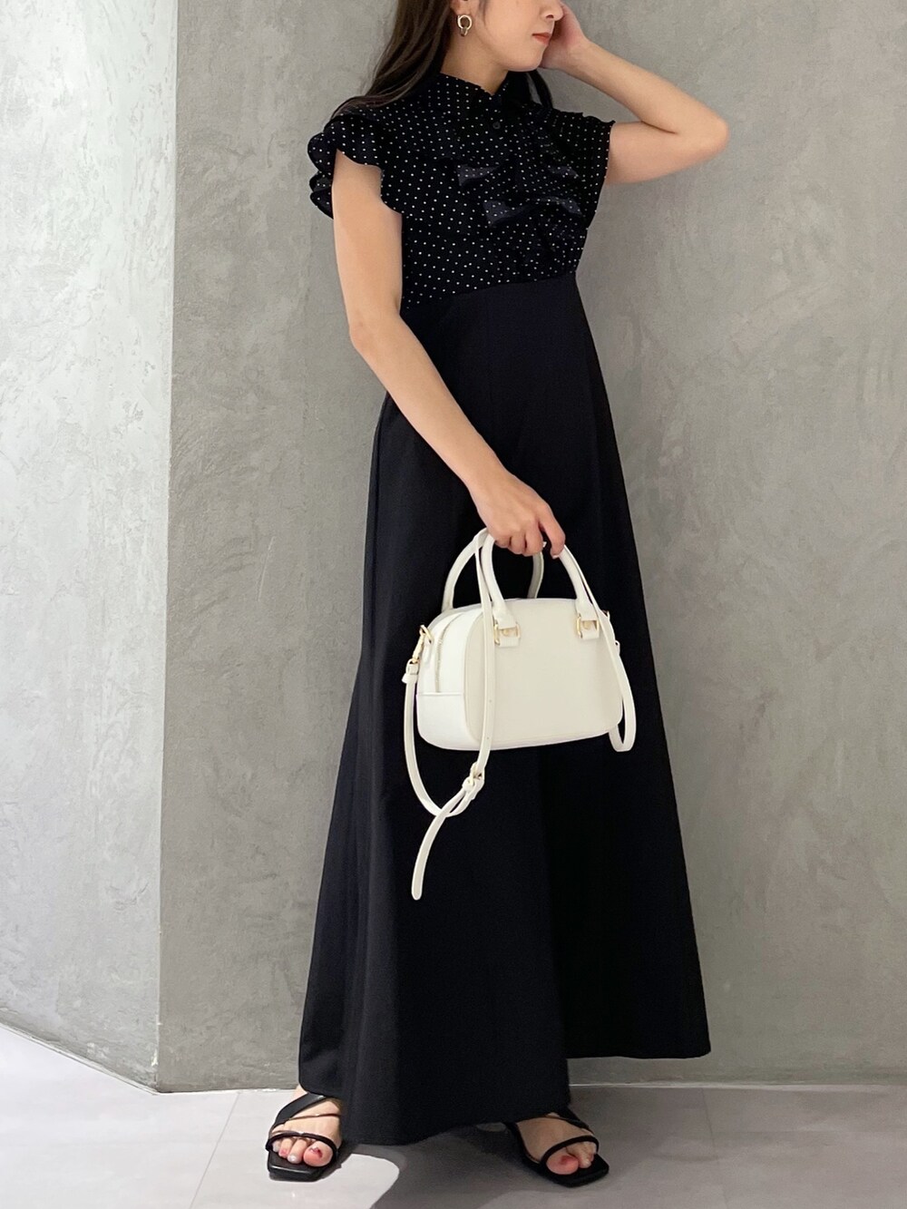 ブラック系のワンピース、ホワイト系のボストンバッグ、ブラック系のサンダルを着用したレディースの春コーディネートの6枚目の写真