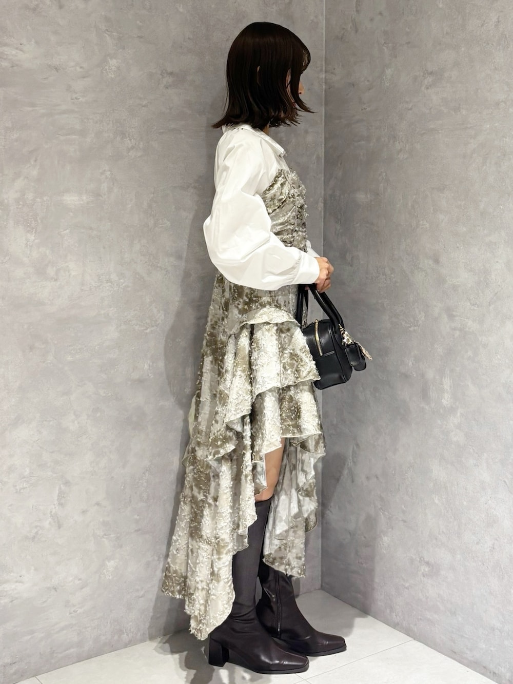 ブラック系のハンドバッグ、ブラウン系のブーツ、グリーン系のワンピースを着用したレディースの秋コーディネートの3枚目の写真