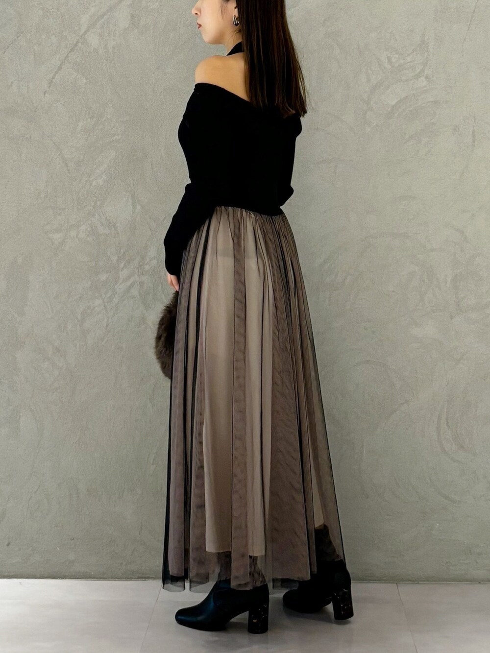 ブラック系のワンピース、ブラック系のブーツ、ブラウン系のハンドバッグを着用したレディースの秋コーディネートの5枚目の写真