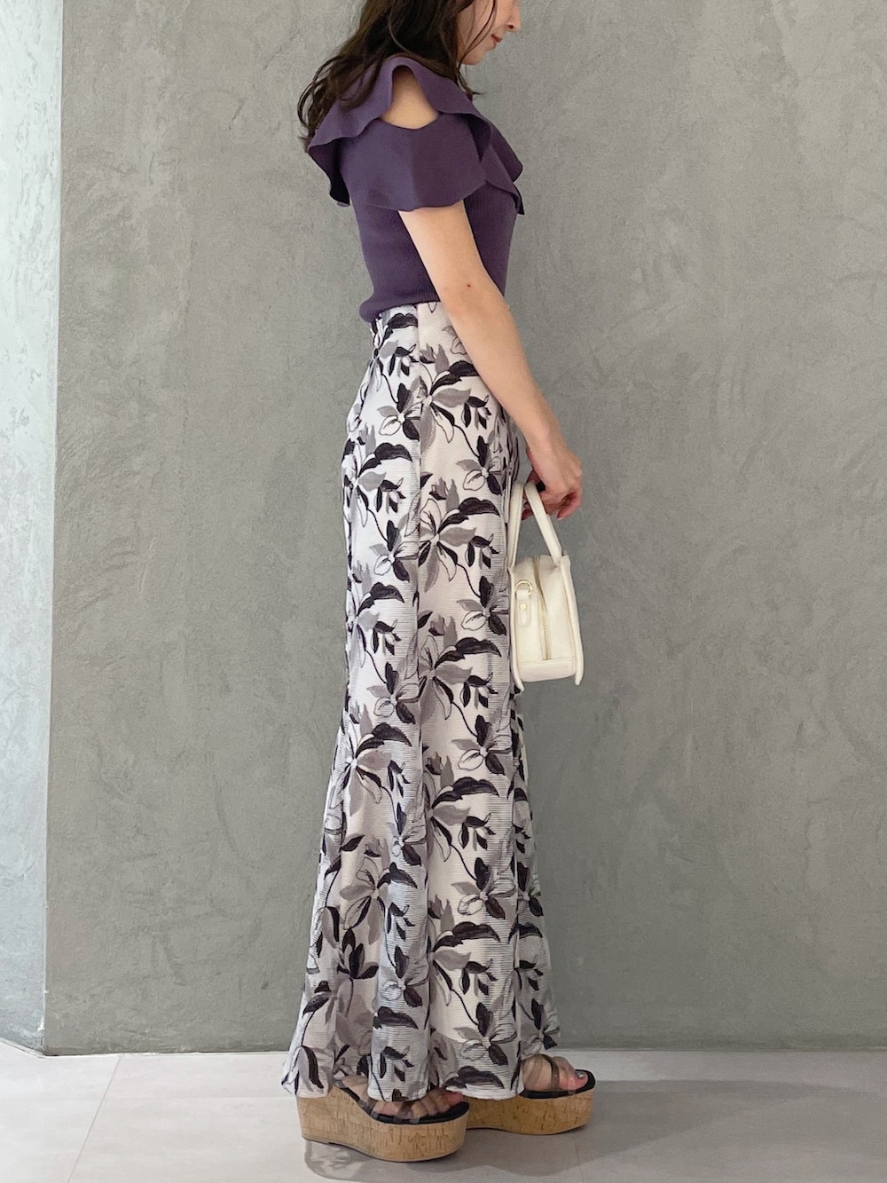 ホワイト系のハンドバッグ、ブラック系のサンダル、パープル系のニット/セーターを着用したレディースの春コーディネートの5枚目の写真