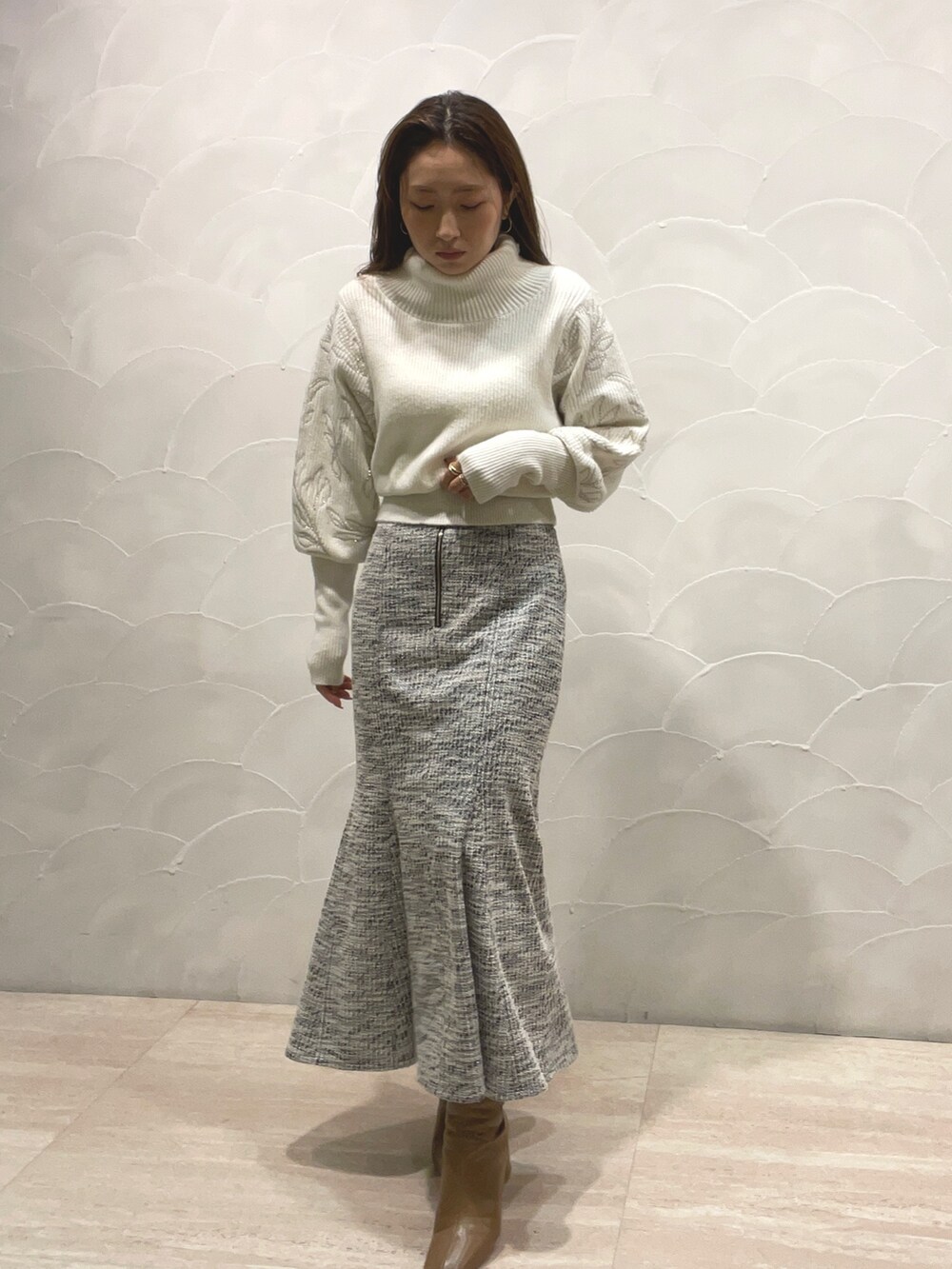 ホワイト系のニット/セーター、ブラック系のスカート、ベージュ系のブーツを着用したレディースの秋コーディネートの3枚目の写真