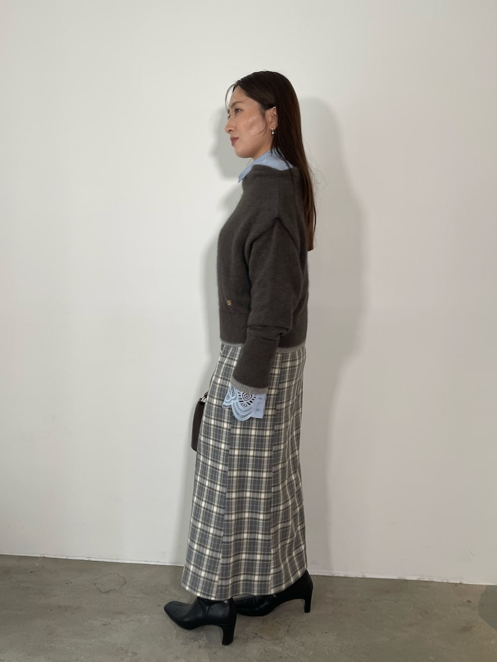 グレー系のスカート、ブラック系のブーツ、ブラウン系のハンドバッグを着用したレディースの秋コーディネートの5枚目の写真