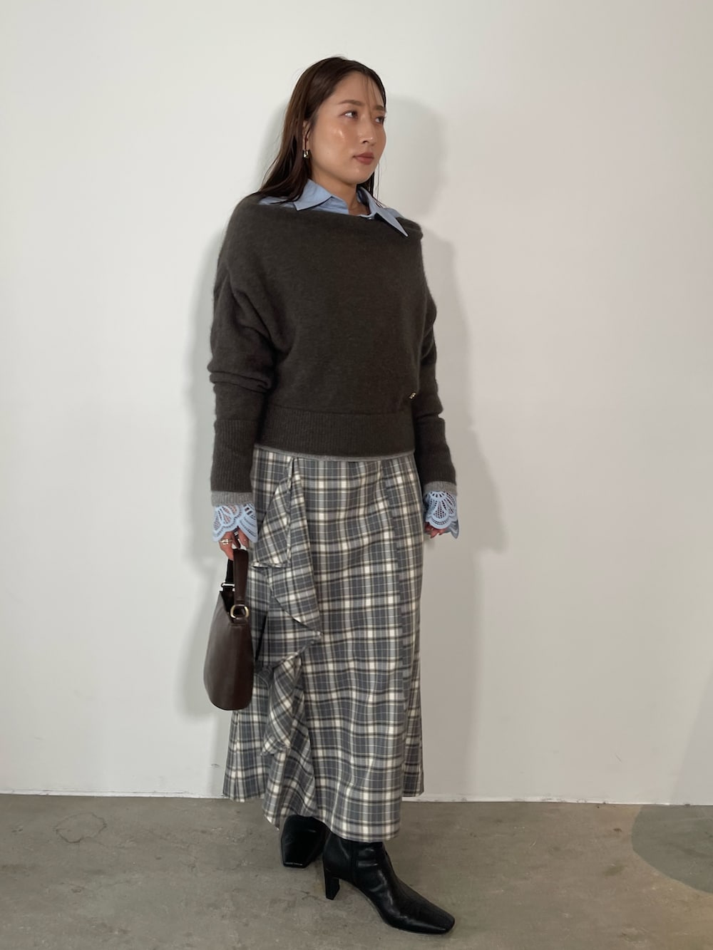グレー系のスカート、ブラック系のブーツ、ブラウン系のハンドバッグを着用したレディースの秋コーディネートの4枚目の写真