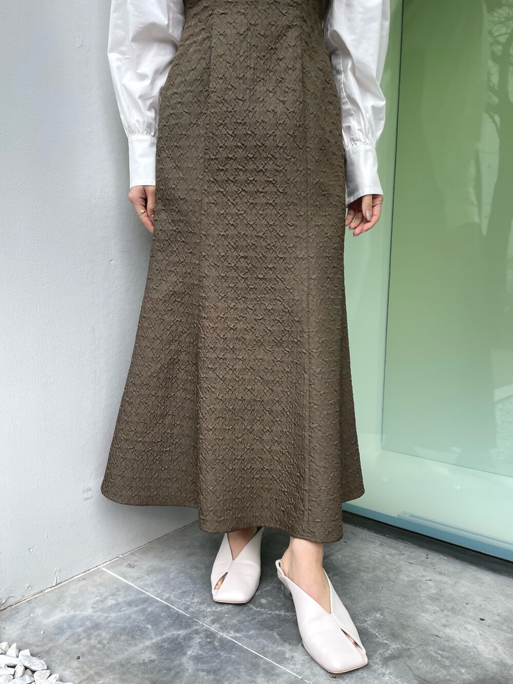 ホワイト系のパンプス、ブラウン系のワンピース、ゴールド系のネックレスを着用したレディースの春コーディネートの10枚目の写真
