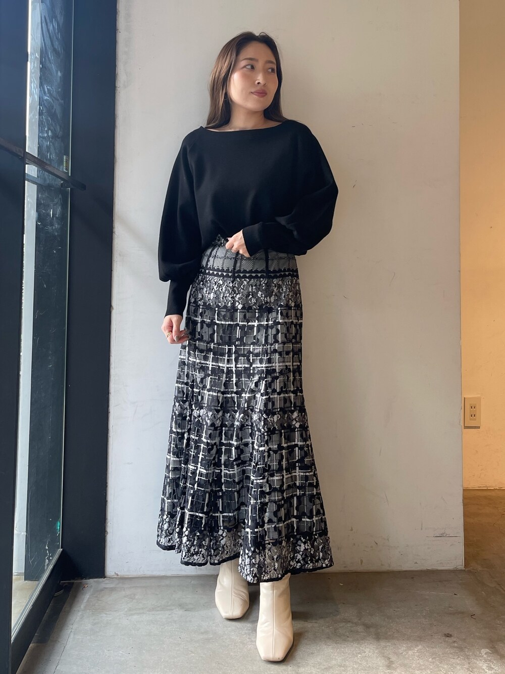 ブラック系のニット/セーター、ホワイト系のブーツ、ブラック系のスカートを着用したレディースの冬コーディネートの2枚目の写真