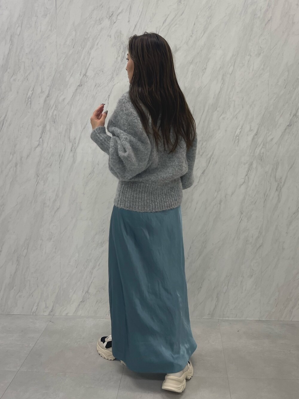 グレー系のニット/セーター、ブルー系のスカート、ブラック系のスニーカーを着用したレディースの冬コーディネートの7枚目の写真