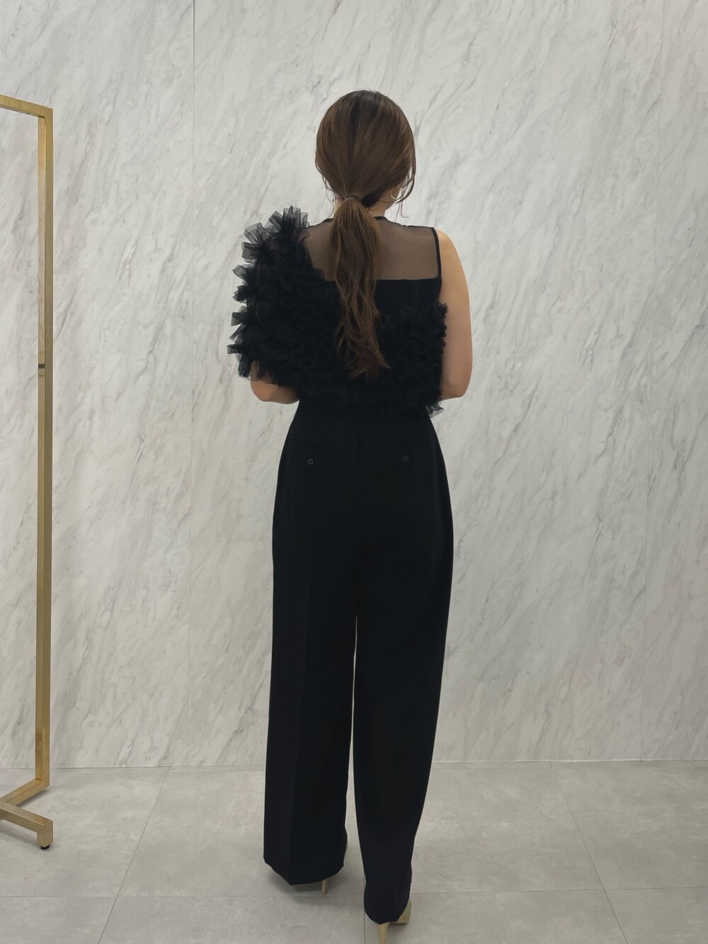 ブラック系のパンツドレス、ゴールド系のパンプスを着用したレディースの冬コーディネートの4枚目の写真