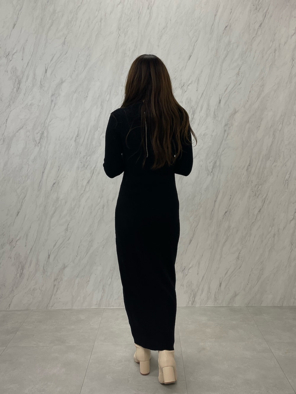 ブラック系のワンピース、ホワイト系のブーツ、ゴールド系のネックレスを着用したレディースの冬コーディネートの5枚目の写真