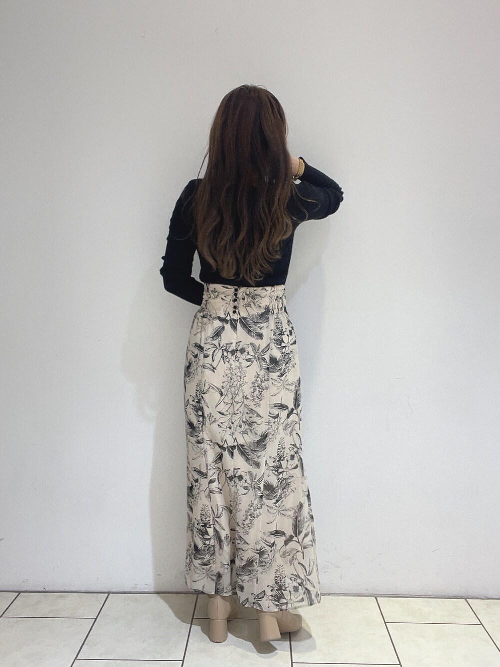 ベージュ系のスカート、ブラック系のニット/セーターを着用したレディースの秋コーディネートの5枚目の写真