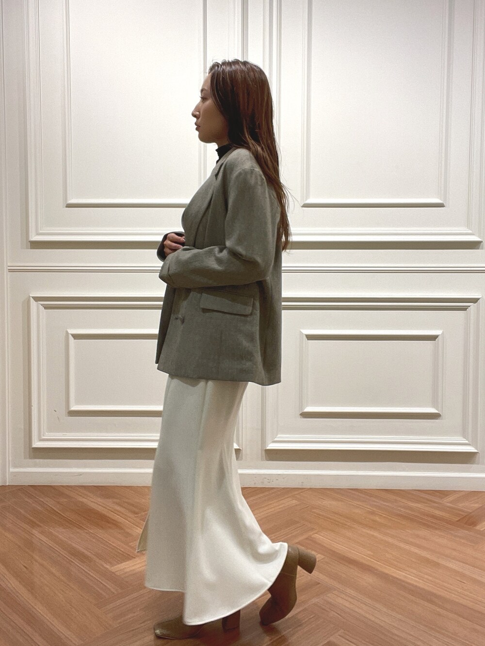 ホワイト系のスカート、ベージュ系のテーラードジャケット、ブラック系のニット/セーターを着用したレディースの秋コーディネートの3枚目の写真