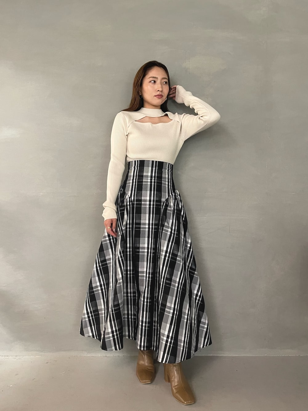 ベージュ系のブーツ、ホワイト系のニット/セーター、ホワイト系のスカートを着用したレディースの秋コーディネートの2枚目の写真