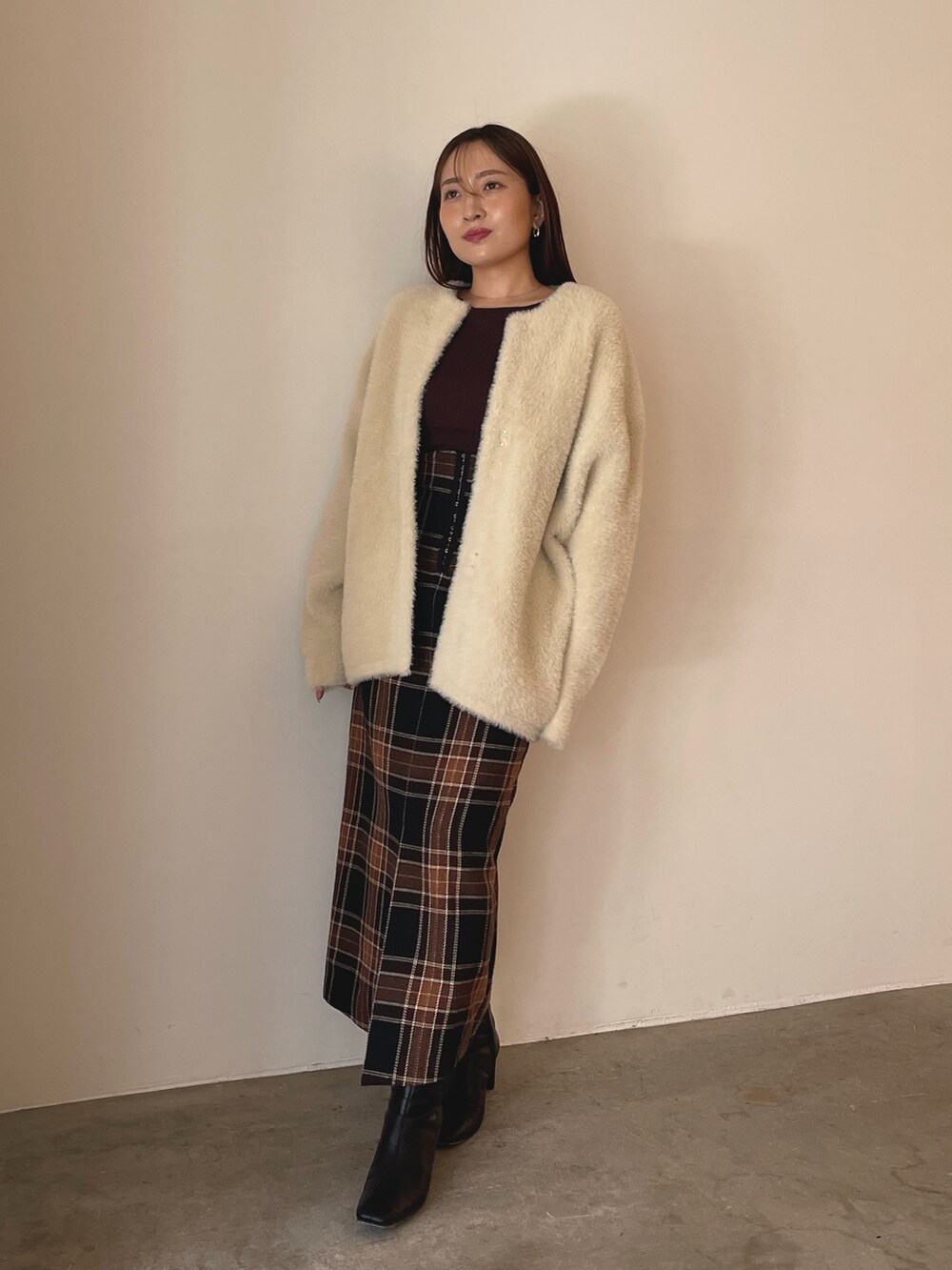 ブラウン系のニット/セーター、ブラウン系のスカート、ブラック系のブーツを着用したレディースの秋コーディネートの5枚目の写真