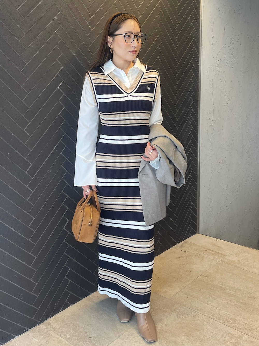 イエロー系のハンドバッグ、ベージュ系のブーツ、グレー系のテーラードジャケットを着用したレディースの冬コーディネートの2枚目の写真