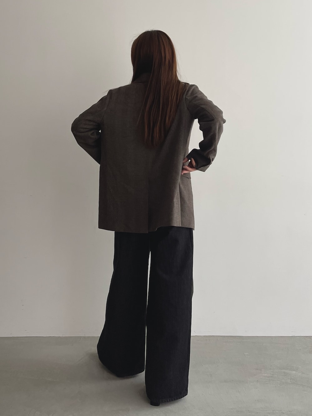 ブラック系のデニムパンツ、グレー系のニット/セーター、ブラウン系のテーラードジャケットを着用したレディースの夏コーディネートの5枚目の写真