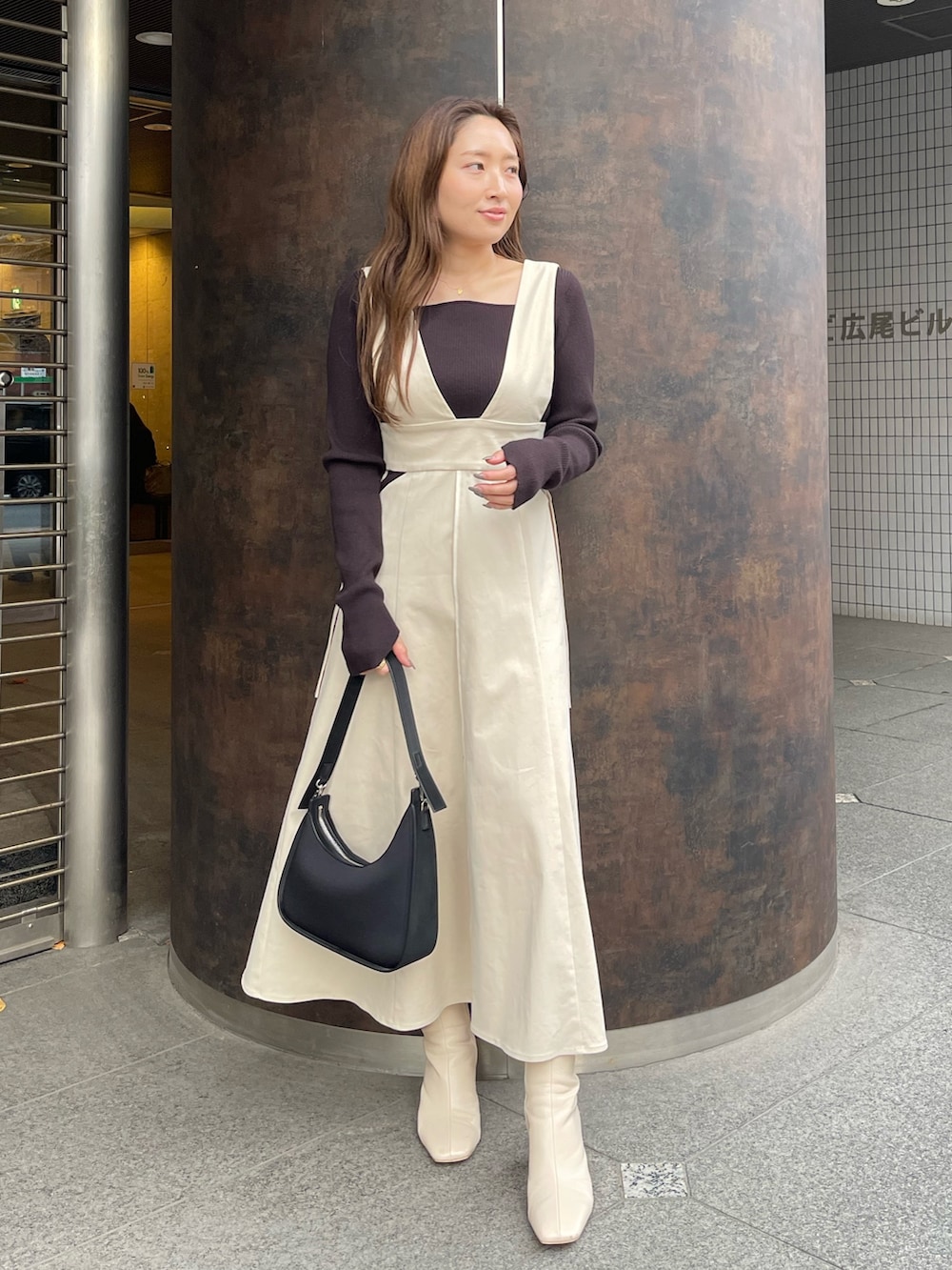 ホワイト系のブーツ、ホワイト系のジャンパースカート、ブラック系のニット/セーターを着用したレディースの冬コーディネートの2枚目の写真