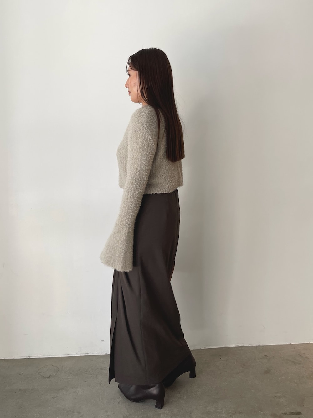 グレー系のアンサンブル、イエロー系のハンドバッグ、ブラウン系のスカートを着用したレディースの秋コーディネートの6枚目の写真