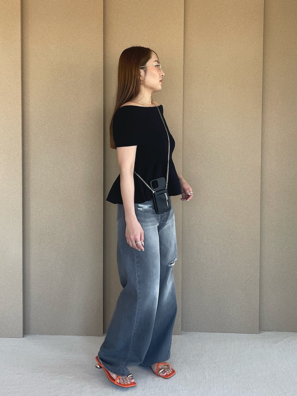 ブラック系のニット/セーター、グレー系のデニムパンツ、オレンジ系のサンダルを着用したレディースの春コーディネートの3枚目の写真