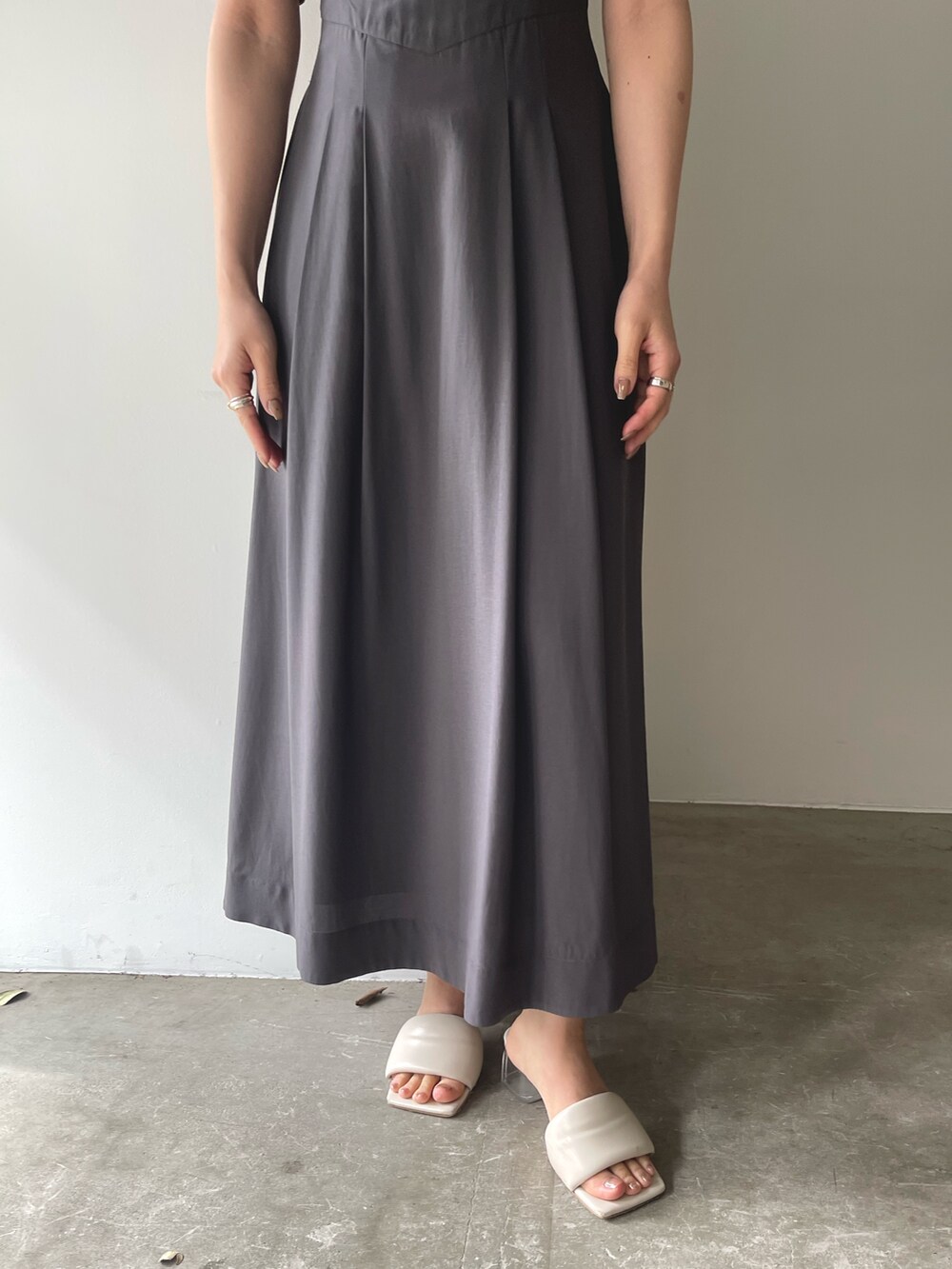 ホワイト系のサンダル、グレー系のワンピース、ゴールド系のピアス（両耳用）を着用したレディースの春コーディネートの9枚目の写真