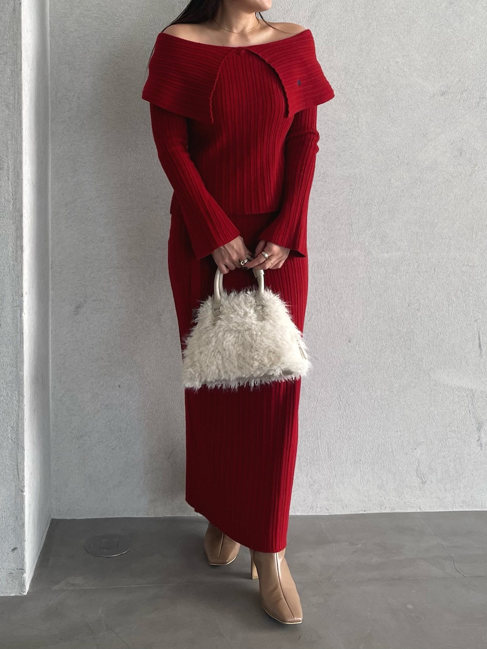 レッド系のニット/セーター、ベージュ系のブーツ、レッド系のスカートを着用したレディースの秋コーディネートの8枚目の写真