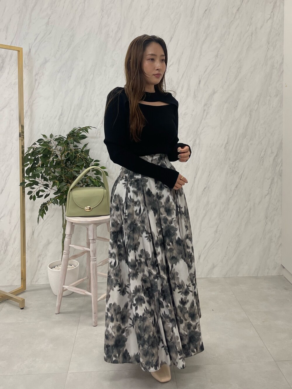 ホワイト系のブーツ、ブラック系のニット/セーター、グリーン系のハンドバッグを着用したレディースの冬コーディネートの2枚目の写真