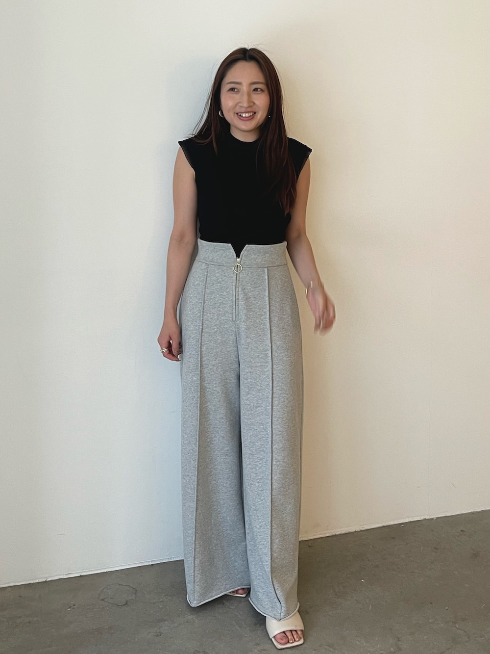 グレー系のスウェットパンツ、ホワイト系のサンダル、ブラック系のニット/セーターを着用したレディースの春コーディネートの2枚目の写真