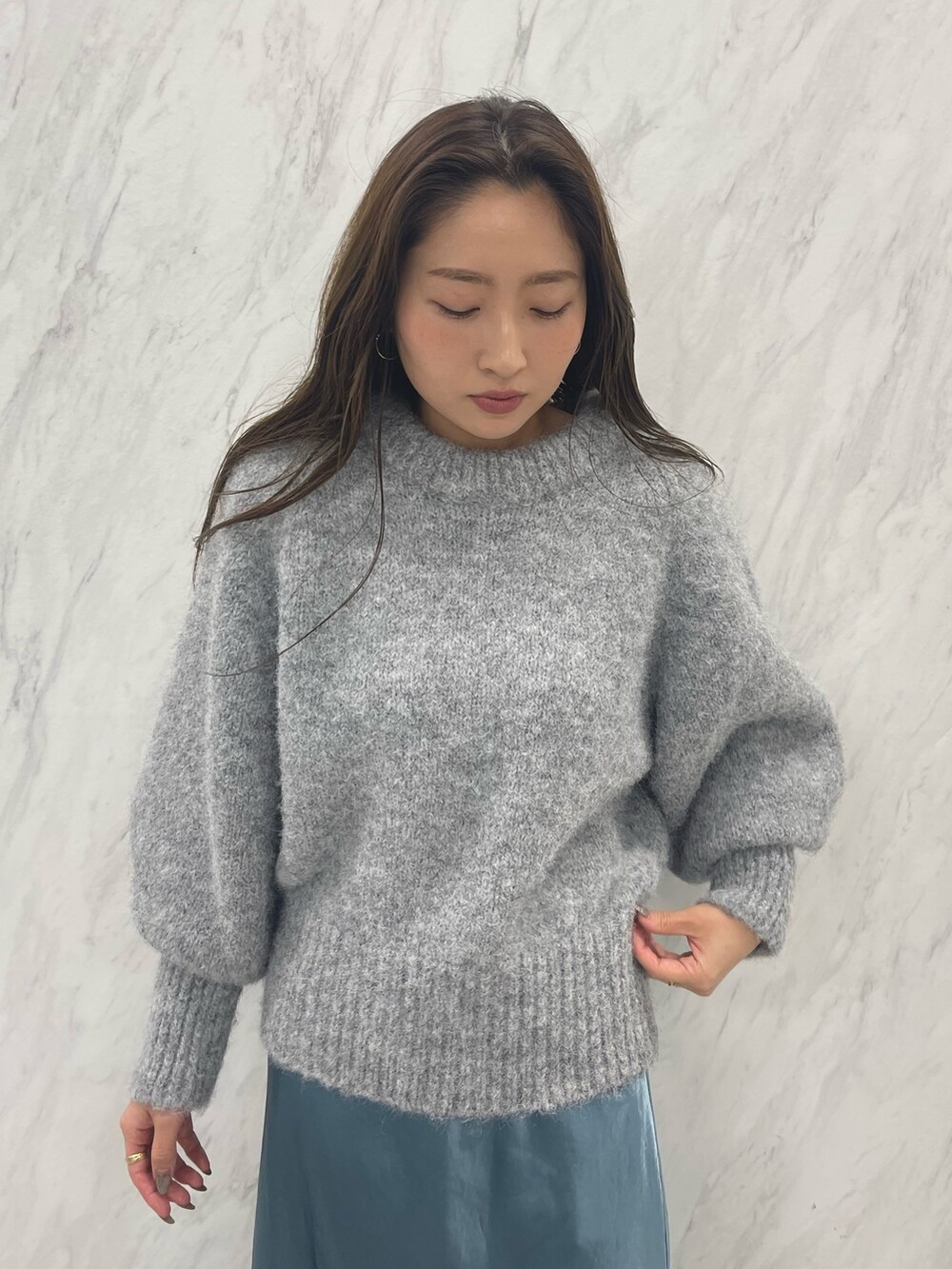 グレー系のニット/セーター、ブルー系のスカート、ブラック系のスニーカーを着用したレディースの冬コーディネートの8枚目の写真