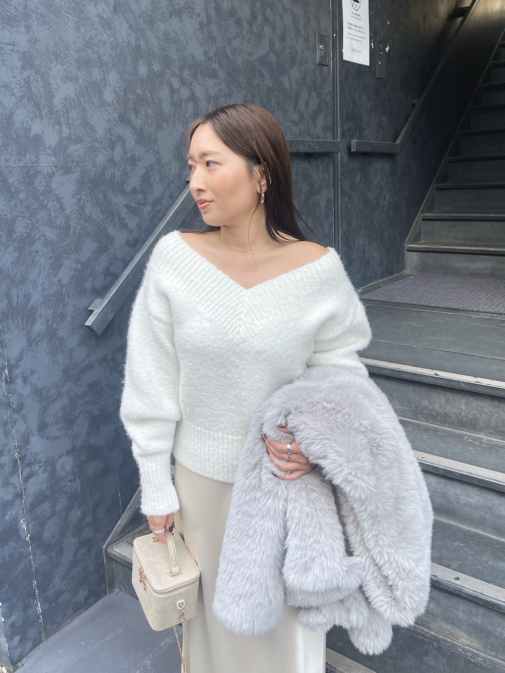 ホワイト系のニット/セーター、グレー系のその他アウター、ゴールド系のハンドバッグを着用したレディースの冬コーディネートの10枚目の写真