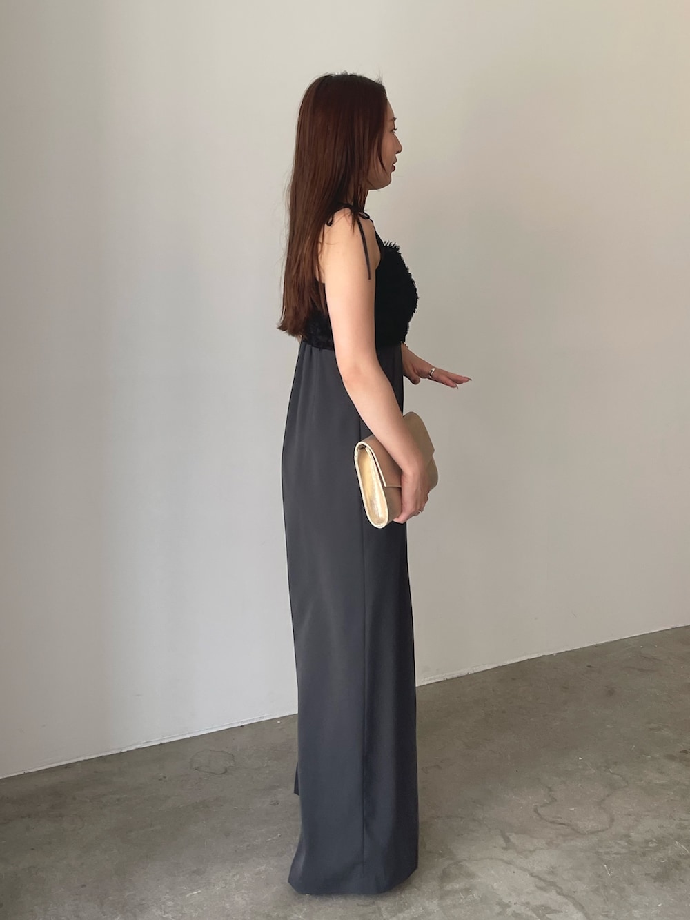 グレー系のパンツドレス、ゴールド系のパンプス、ゴールド系のクラッチバッグを着用したレディースの春コーディネートの6枚目の写真