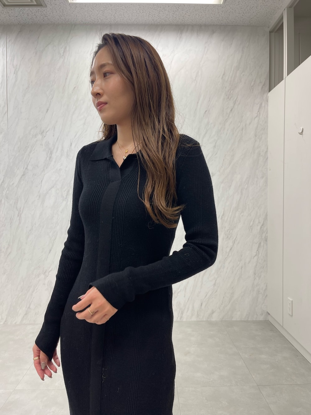 ブラック系のワンピース、ホワイト系のブーツ、ゴールド系のネックレスを着用したレディースの冬コーディネートの6枚目の写真