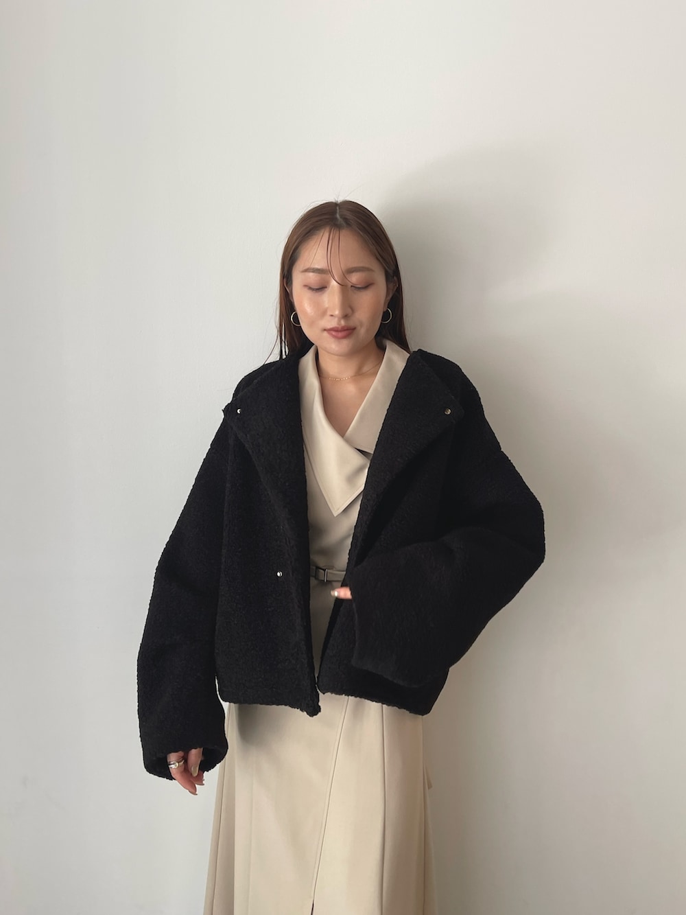 イエロー系のハンドバッグ、ブラック系のブルゾン、ベージュ系のワンピースを着用したレディースの秋コーディネートの6枚目の写真