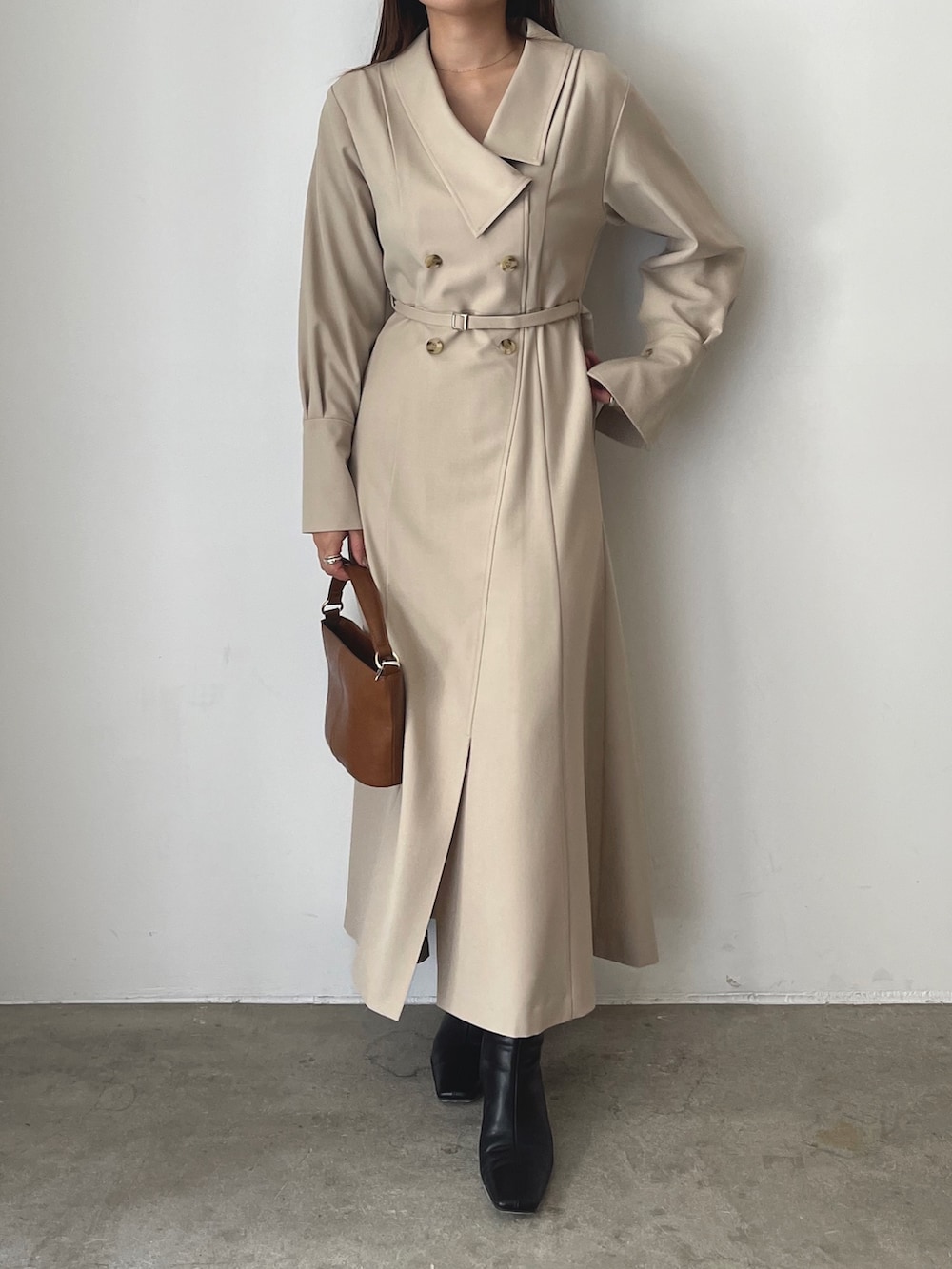 ブラック系のブーツ、ベージュ系のワンピース、イエロー系のハンドバッグを着用したレディースの秋コーディネートの2枚目の写真