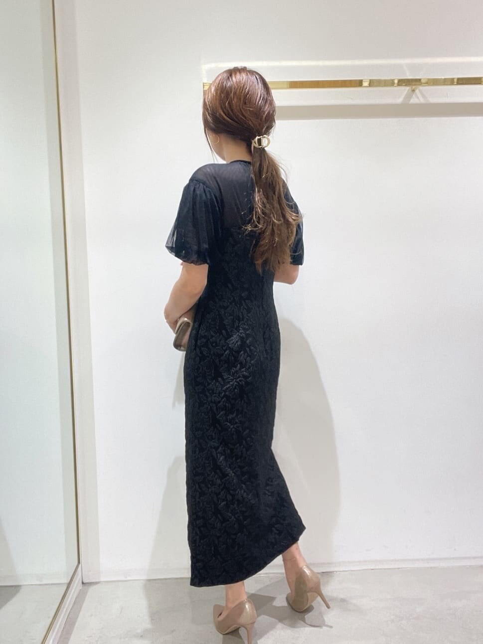 ゴールド系のクラッチバッグ、ゴールド系のパンプス、ブラック系のドレスを着用したレディースの秋コーディネートの7枚目の写真