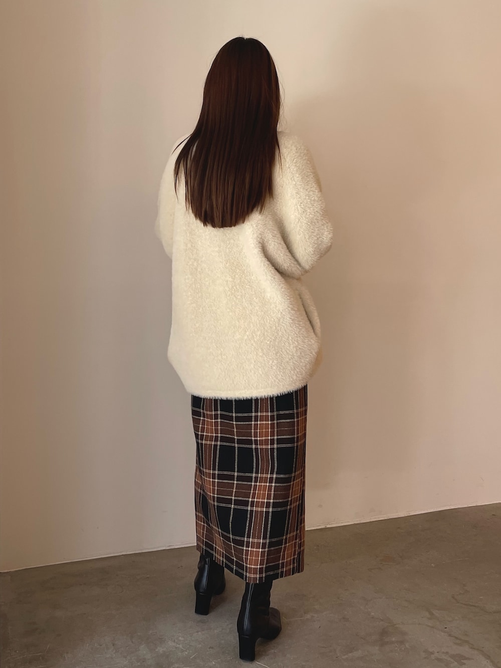 ブラウン系のニット/セーター、ブラウン系のスカート、ブラック系のブーツを着用したレディースの秋コーディネートの6枚目の写真