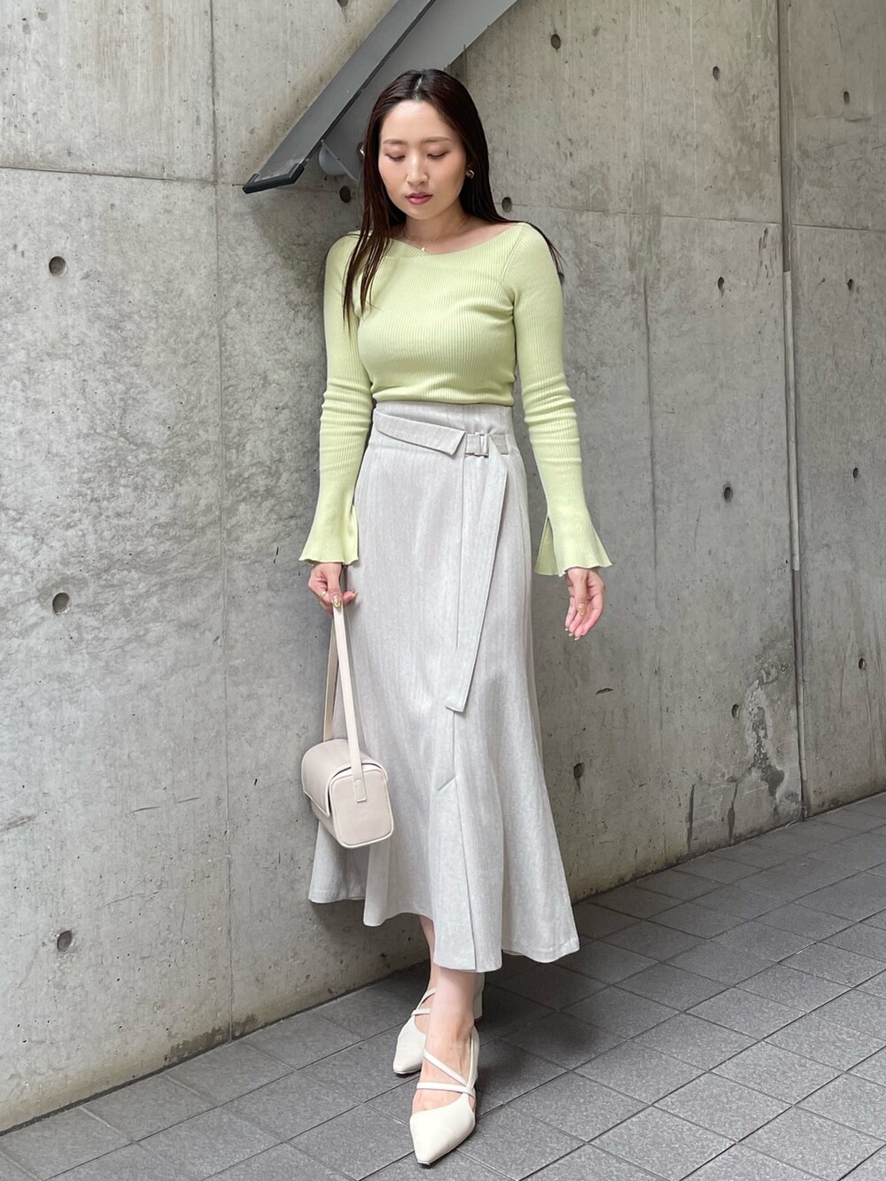 ホワイト系のショルダーバッグ、ホワイト系のパンプス、グレー系のスカートを着用したレディースの秋コーディネートの2枚目の写真