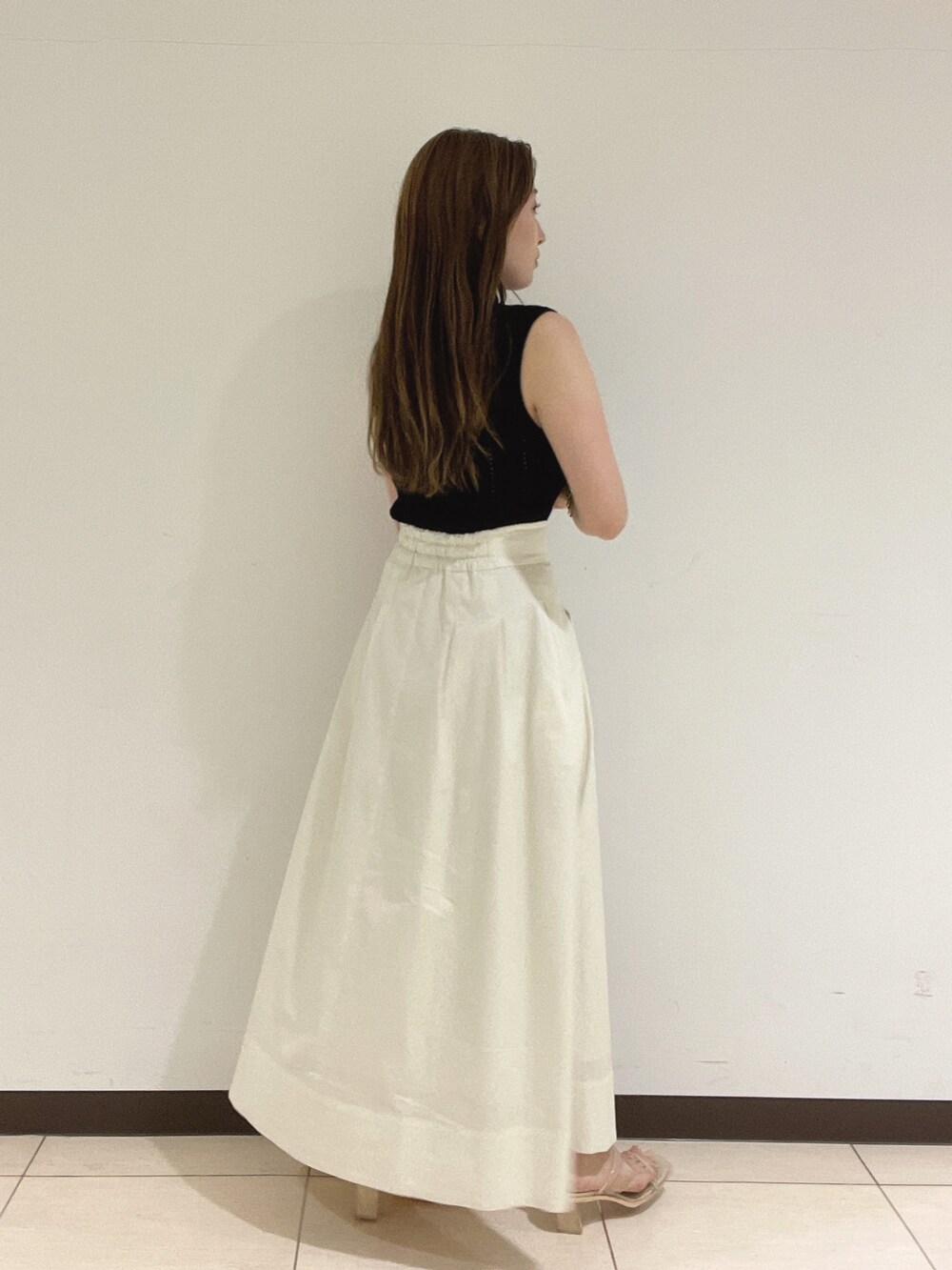 ブラック系のニット/セーター、ホワイト系のスカート、その他のサンダルを着用したレディースの夏コーディネートの6枚目の写真