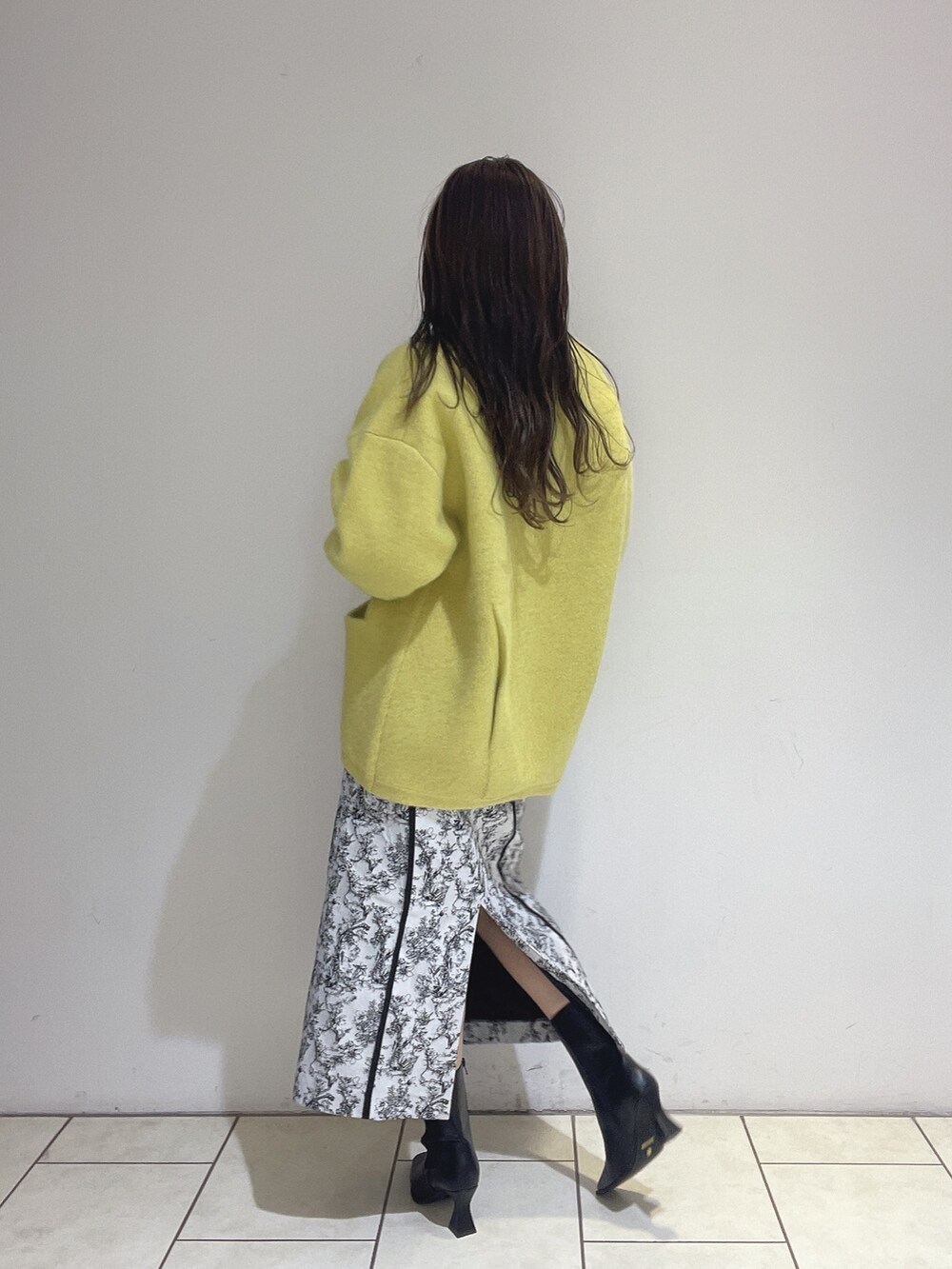 イエロー系のカーディガン/ボレロ、ブラック系のスカート、ホワイト系のニット/セーターを着用したレディースの秋コーディネートの5枚目の写真