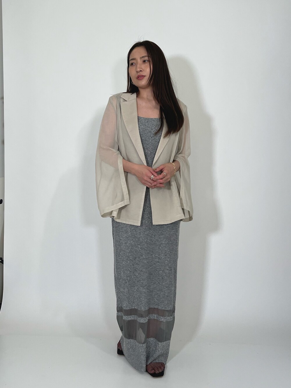 ホワイト系のテーラードジャケット、グレー系のワンピース、ブラック系のサンダルを着用したレディースの夏コーディネートの2枚目の写真