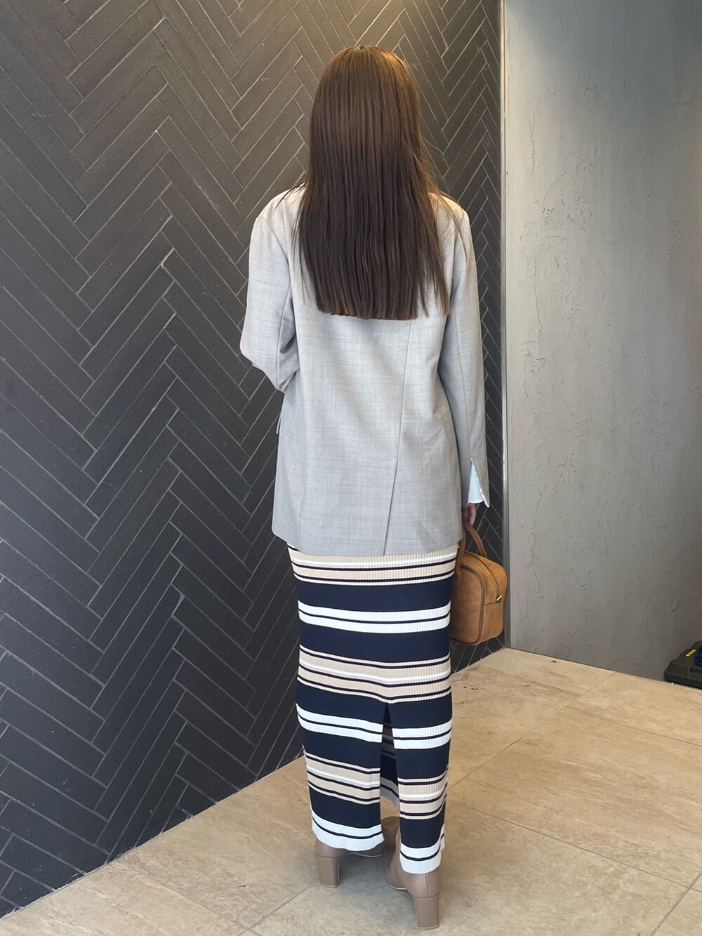 イエロー系のハンドバッグ、ベージュ系のワンピース、グレー系のテーラードジャケットを着用したレディースの冬コーディネートの6枚目の写真