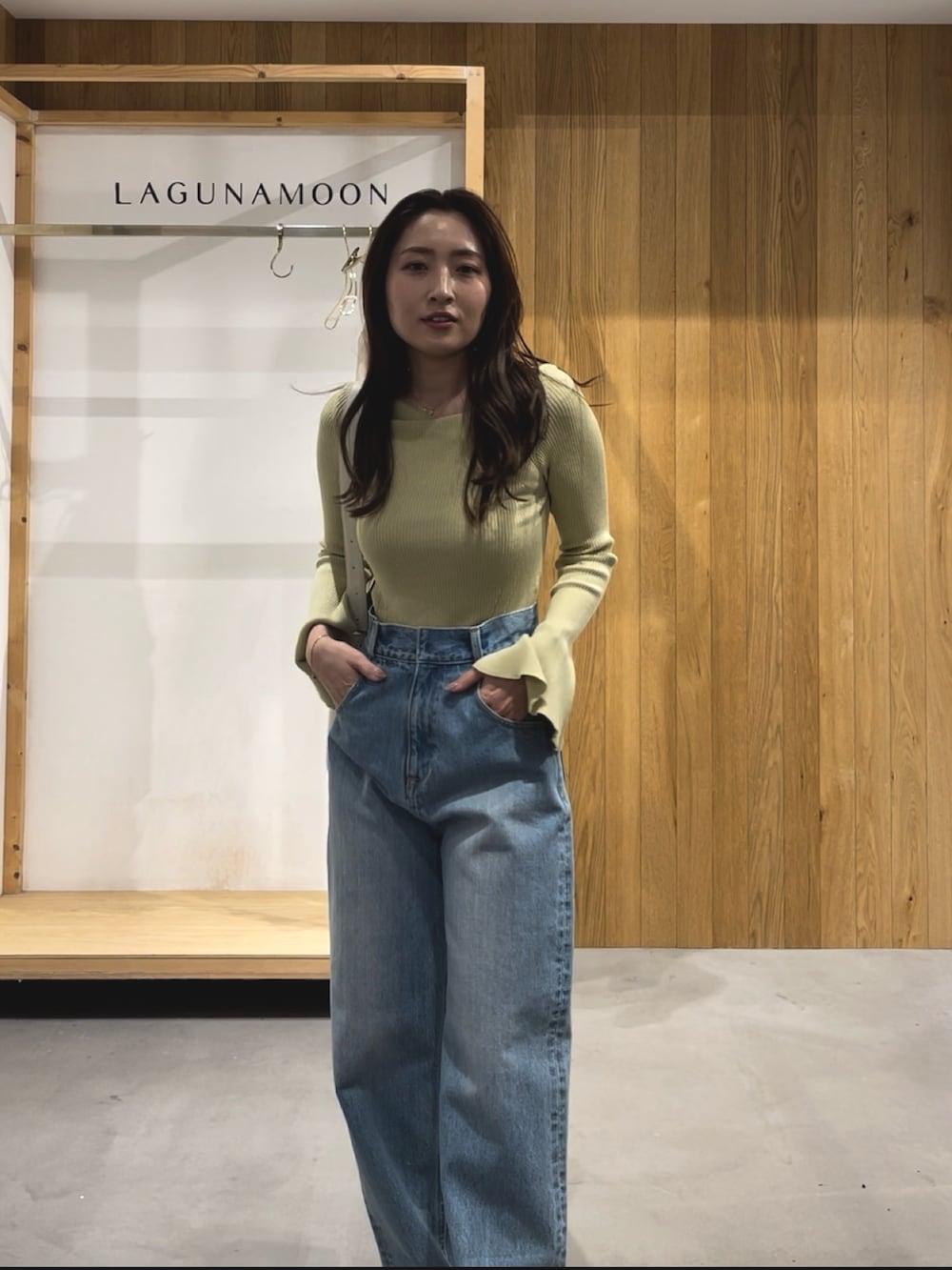グリーン系のニット/セーター、ホワイト系のパンプス、ブルー系のデニムパンツを着用したレディースの冬コーディネートの3枚目の写真