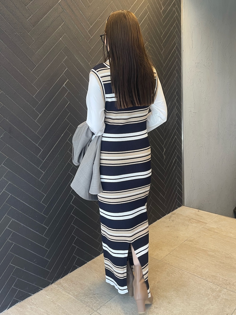 イエロー系のハンドバッグ、ベージュ系のブーツ、グレー系のテーラードジャケットを着用したレディースの冬コーディネートの6枚目の写真