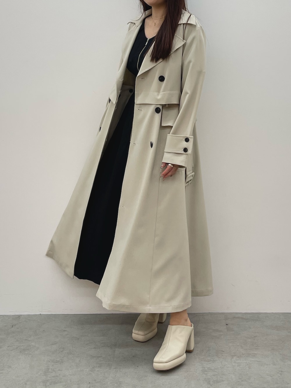 ホワイト系のトレンチコート、ブラック系のワンピース、ホワイト系のサンダルを着用したレディースの春コーディネートの5枚目の写真