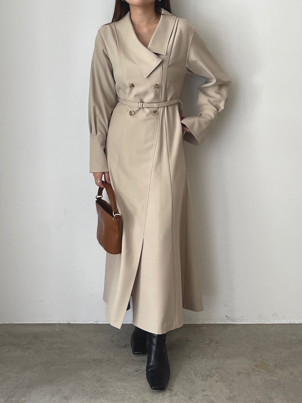 イエロー系のハンドバッグ、ブラック系のブルゾン、ベージュ系のワンピースを着用したレディースの秋コーディネートの8枚目の写真