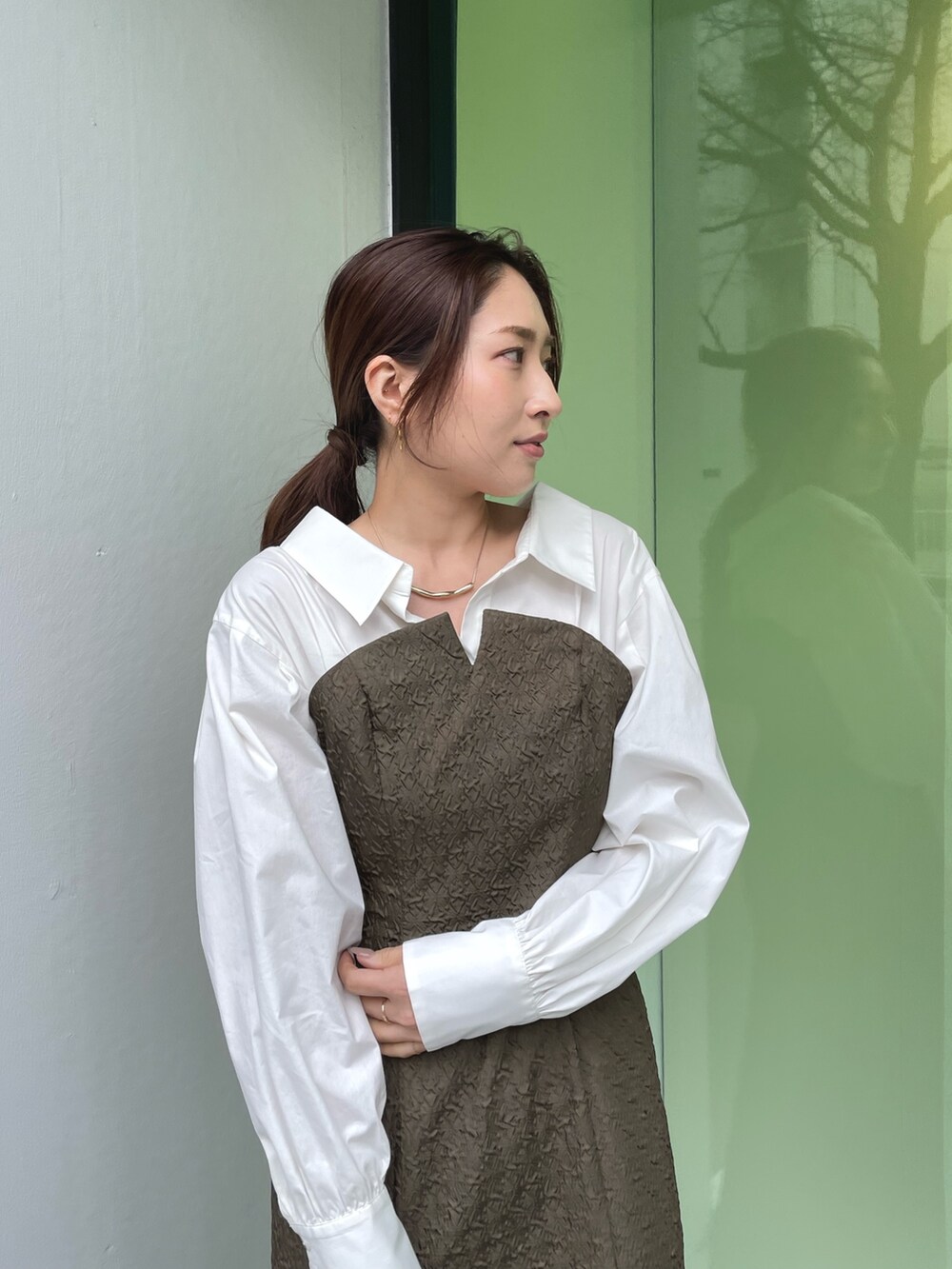 ホワイト系のパンプス、ブラウン系のワンピース、ゴールド系のネックレスを着用したレディースの春コーディネートの8枚目の写真