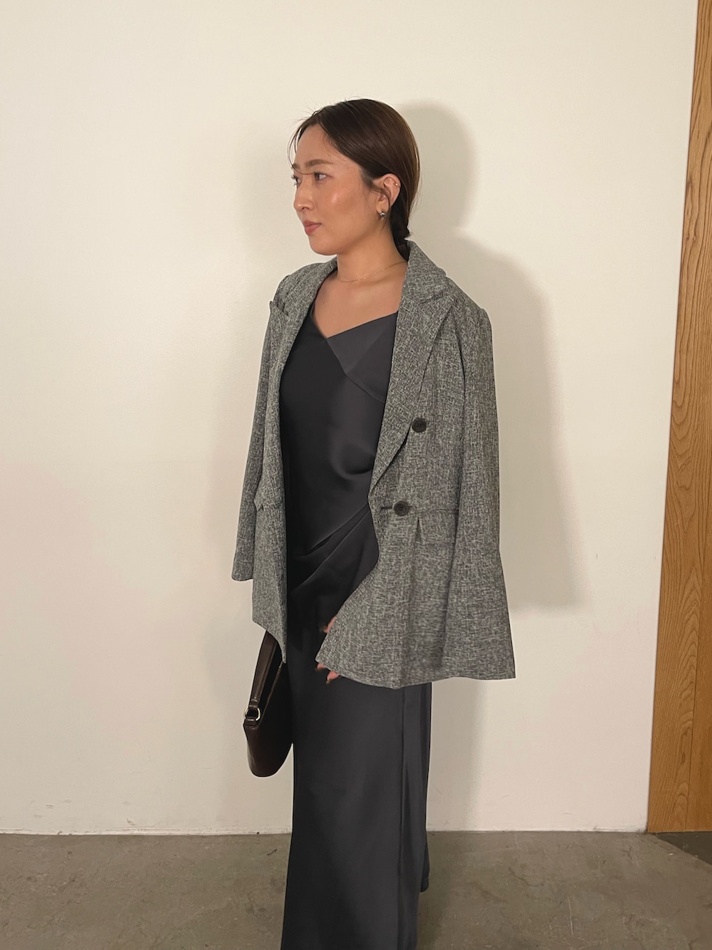 グレー系のドレス、ブラウン系のハンドバッグ、ゴールド系のパンプスを着用したレディースの冬コーディネートの7枚目の写真