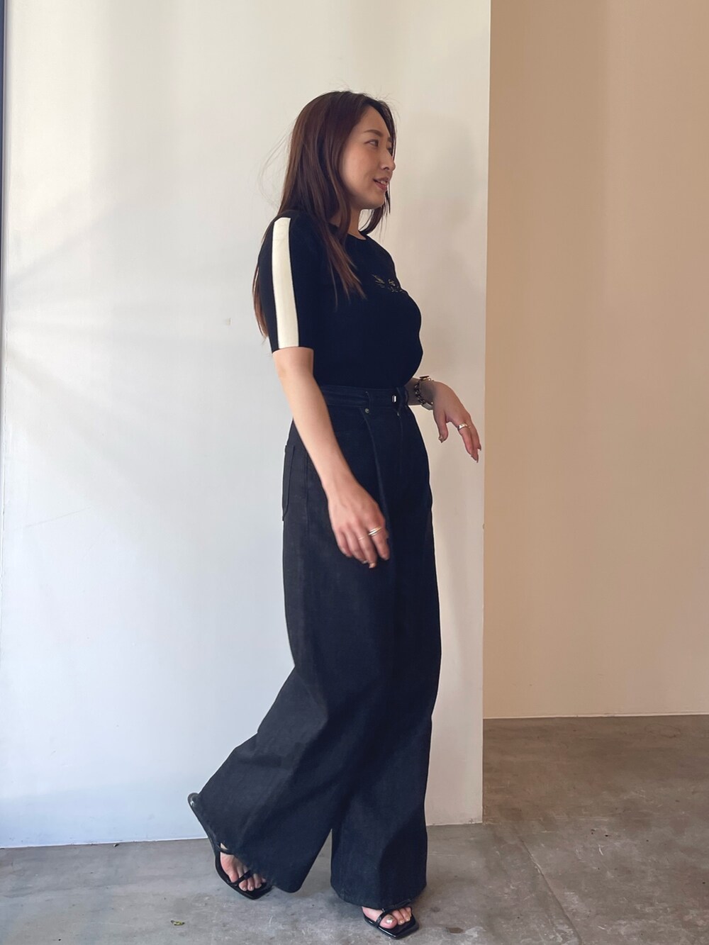 ブラック系のサンダル、ブラック系のニット/セーター、ブラック系のデニムパンツを着用したレディースの夏コーディネートの4枚目の写真